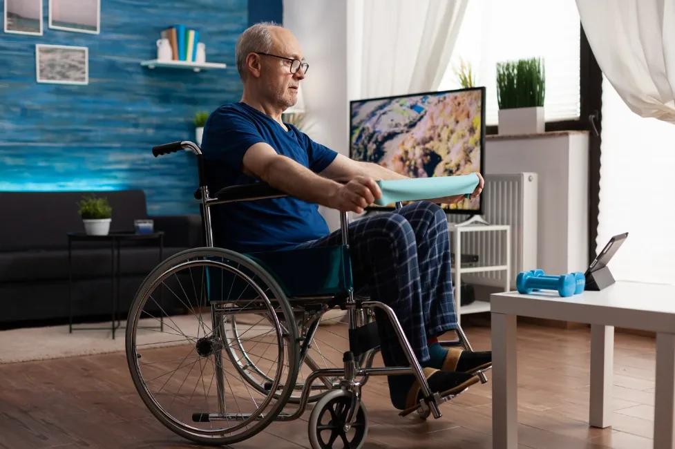 Handicapped old man in wheelchair training arm resistance exercising body