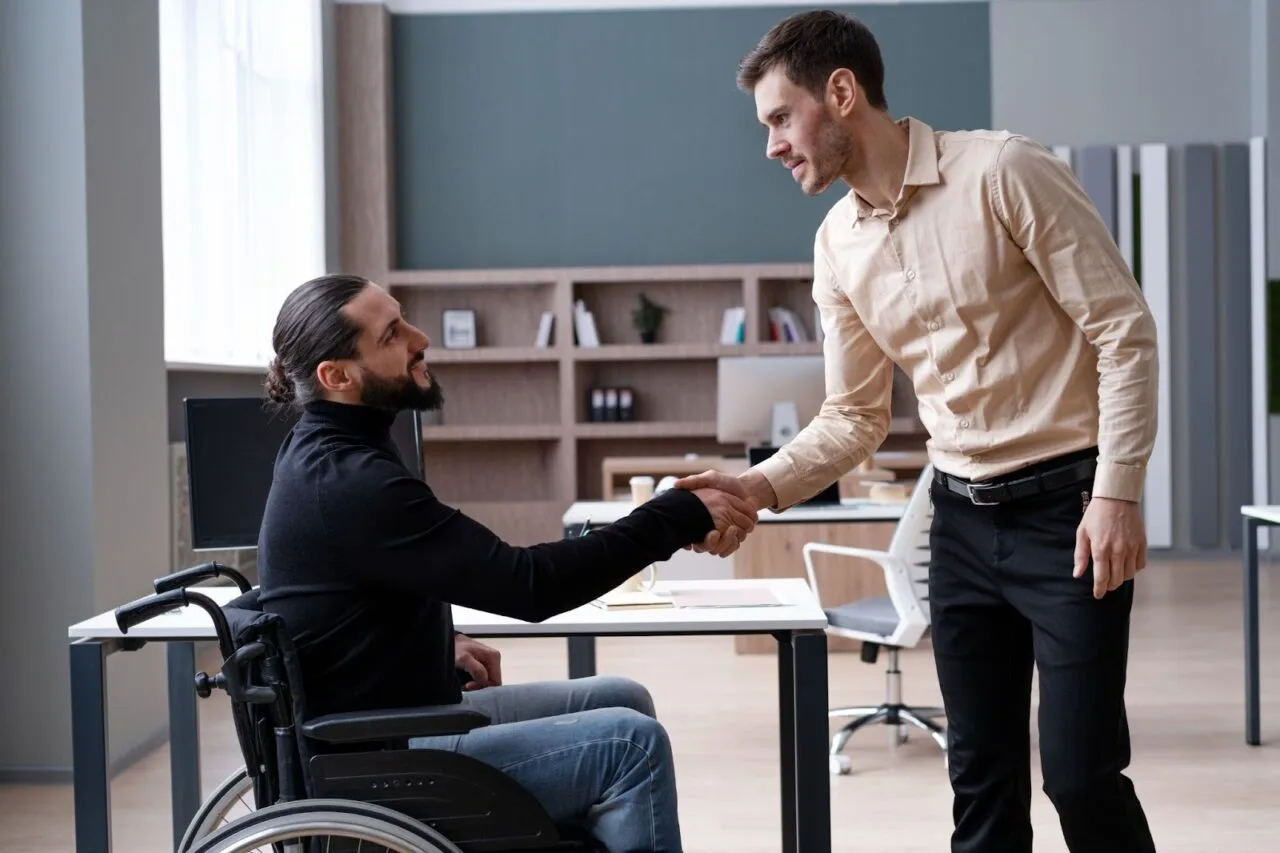 European Accessibility Act: a business team shaking hands with a colleague who uses a wheelchair